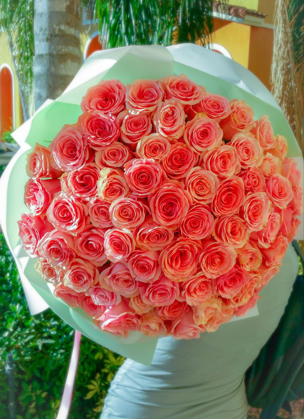 Close-up view of a vibrant bouquet of 50 roses in various colors, arranged elegantly with green leaves surrounding the blooms.