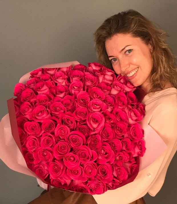 Vibrant bouquet of hot pink roses with lush green foliage, showcasing bold, rich petals in a stunning, lively arrangement full of energy and passion.