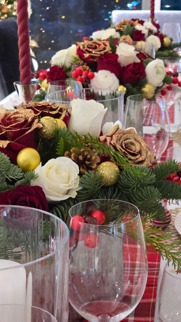 Decorative floral arrangement with red, gold, and green elements on a table.